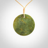 This piece is a medium sized, oval round, disc pendant. It is suspended on a beige coloured braided cord that is length adjustable.